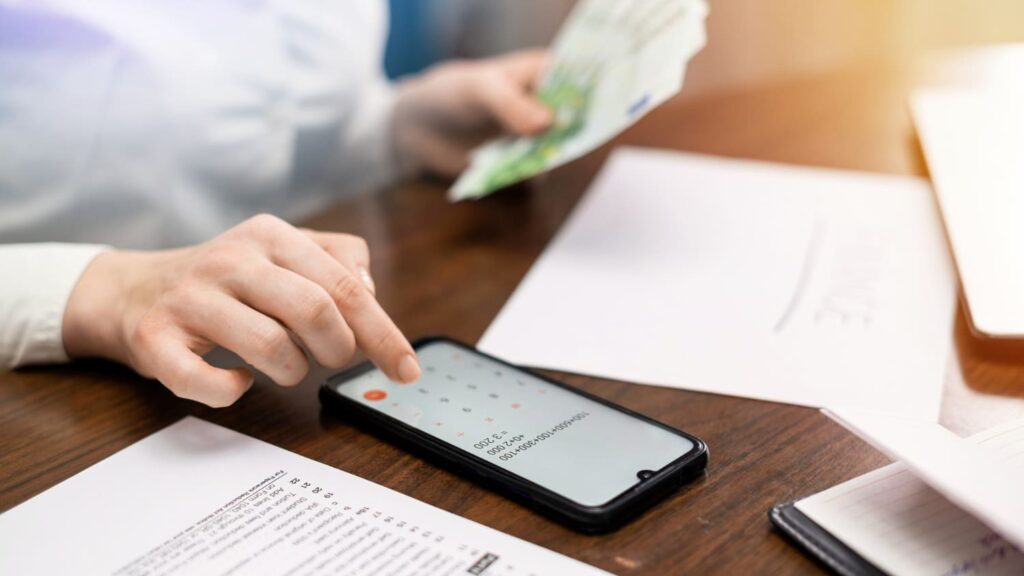 An individual using a smartphone and reviewing financial information related to tax and accounting services in Hollywood, FL